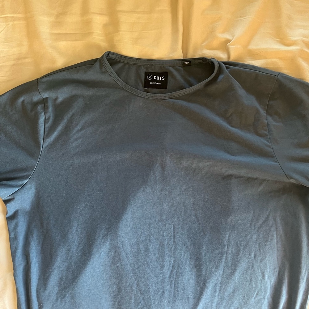 Cuts curved hem t shirts. One black, one dark blue, one light blue.